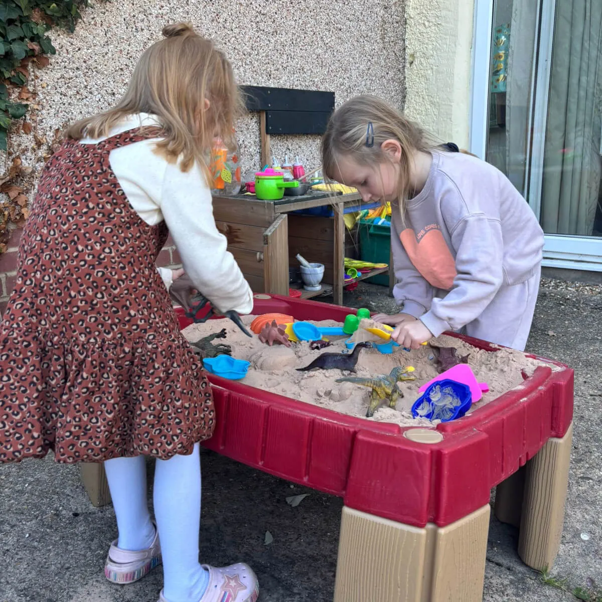 Two girls playing in sand pit